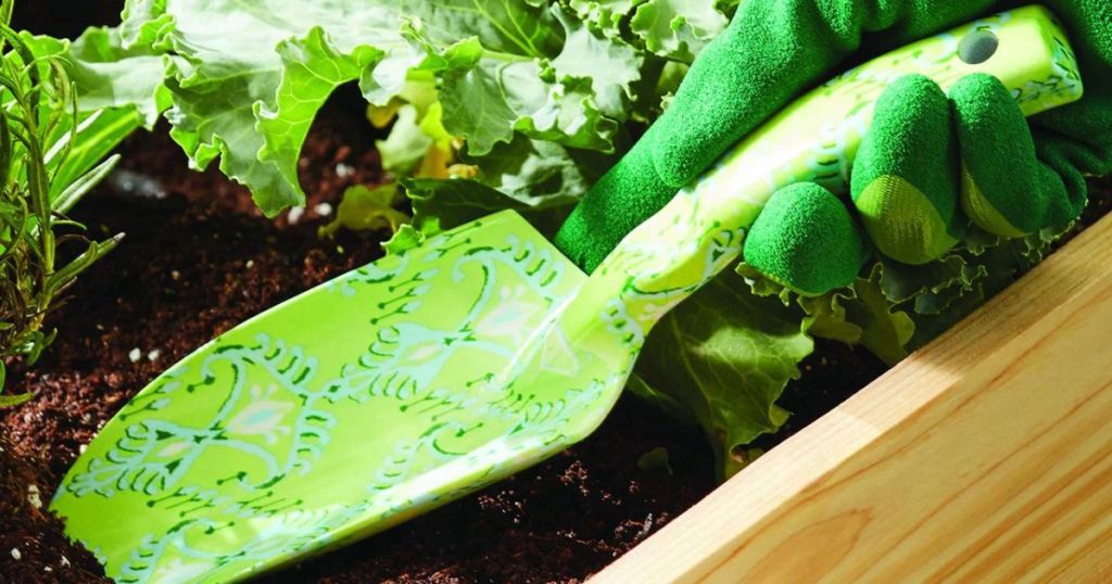 a shovel digging into a garden with some lettuce growing 