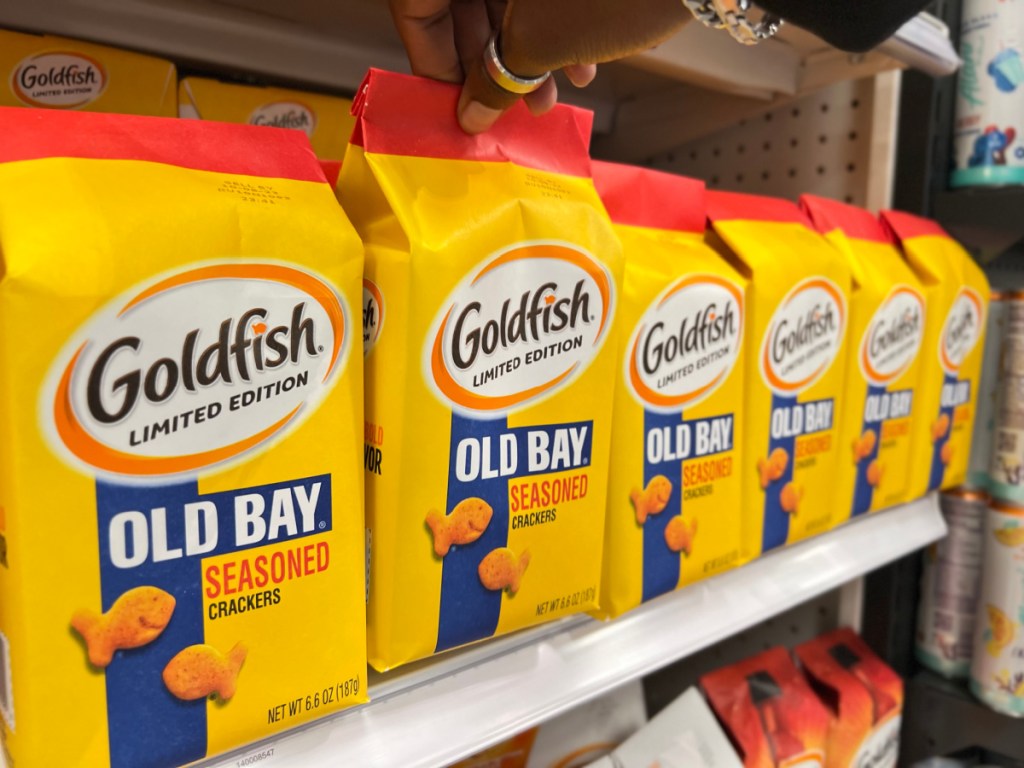 bags of limited edition old bay goldfish crackers lined up on a store shelf with a hand reaching for one bag