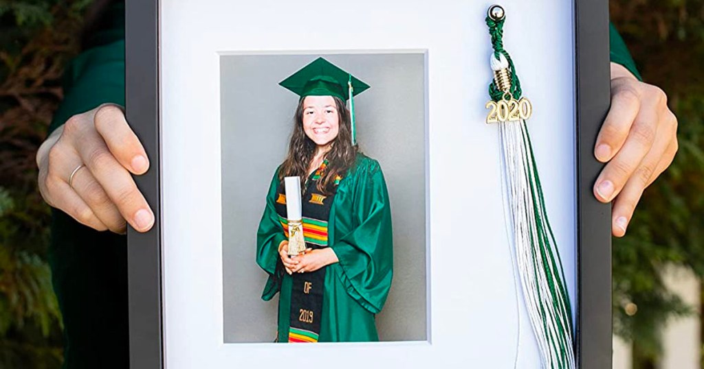 hands holding graduation picture frame with tassle and photo