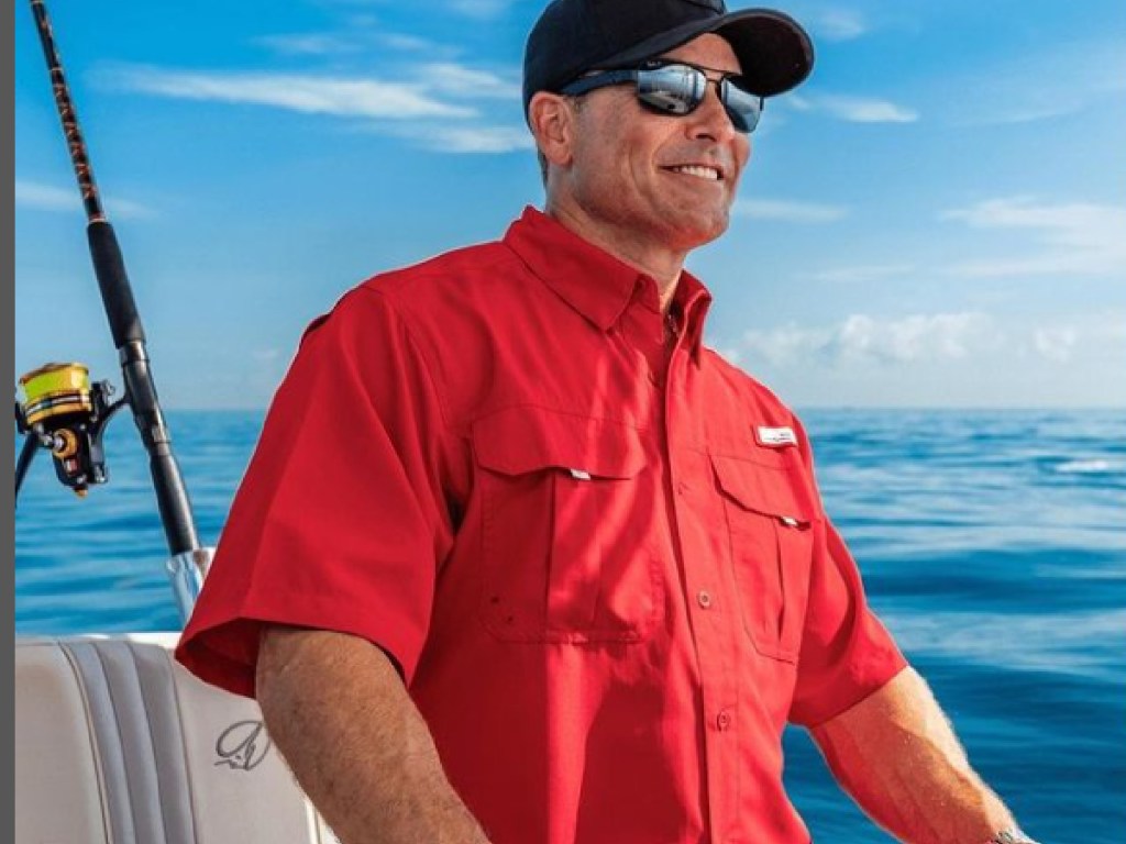 man in a red habig fishing shirt driving a boat