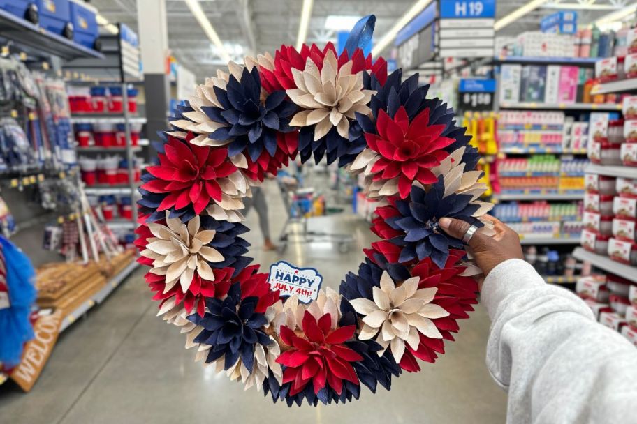 a woman hand holding up a red white and blue wood chip wreath