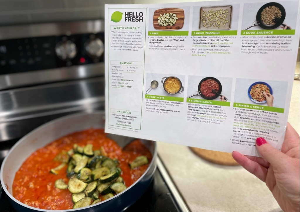 holding recipe card over pot of food on stove