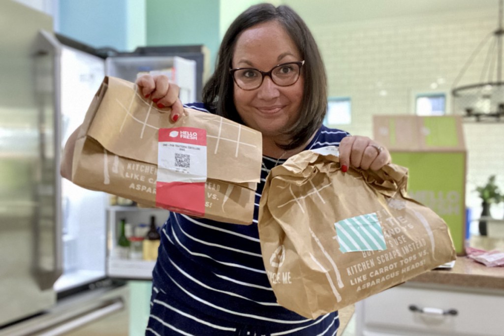 woman holding two brown paper hello fresh bags