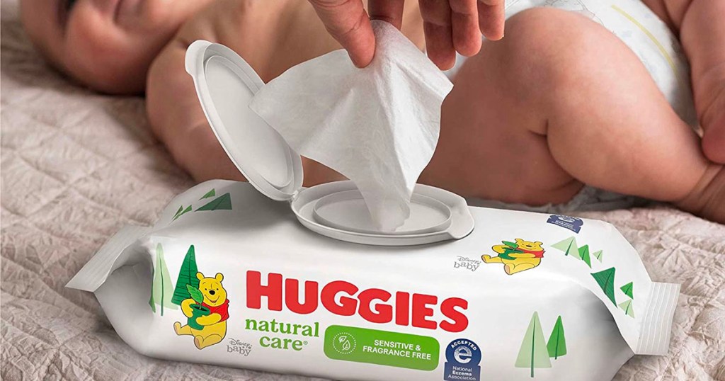 hand taking wipes out of huggies wipe package with baby in background