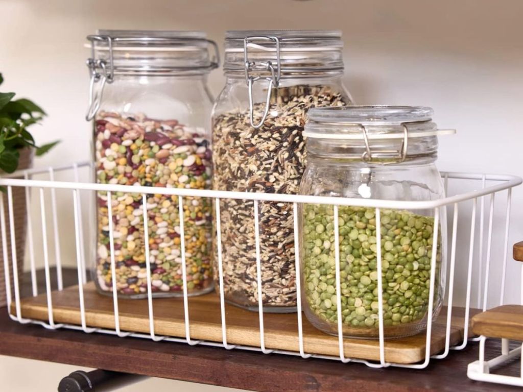 iDesign wire and acacia wood storage bin with jars of pantry staples in it