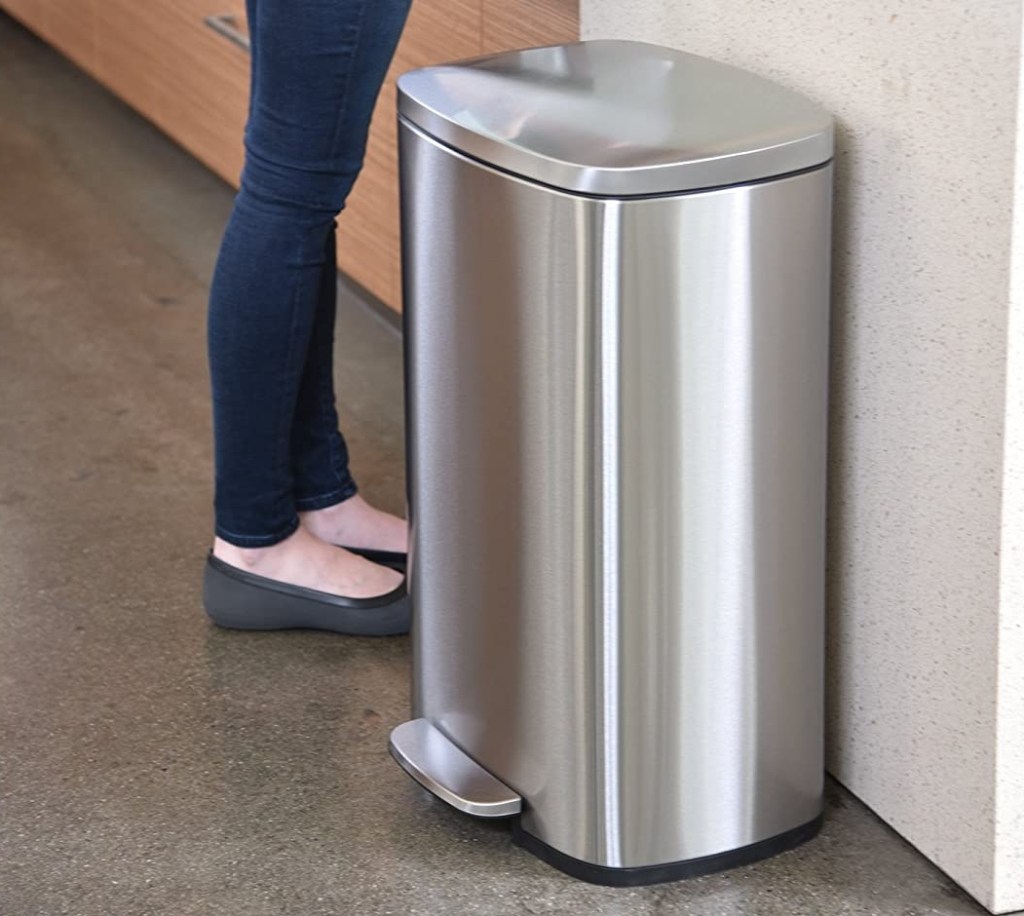 Woman standing next to a stainless steel trash can