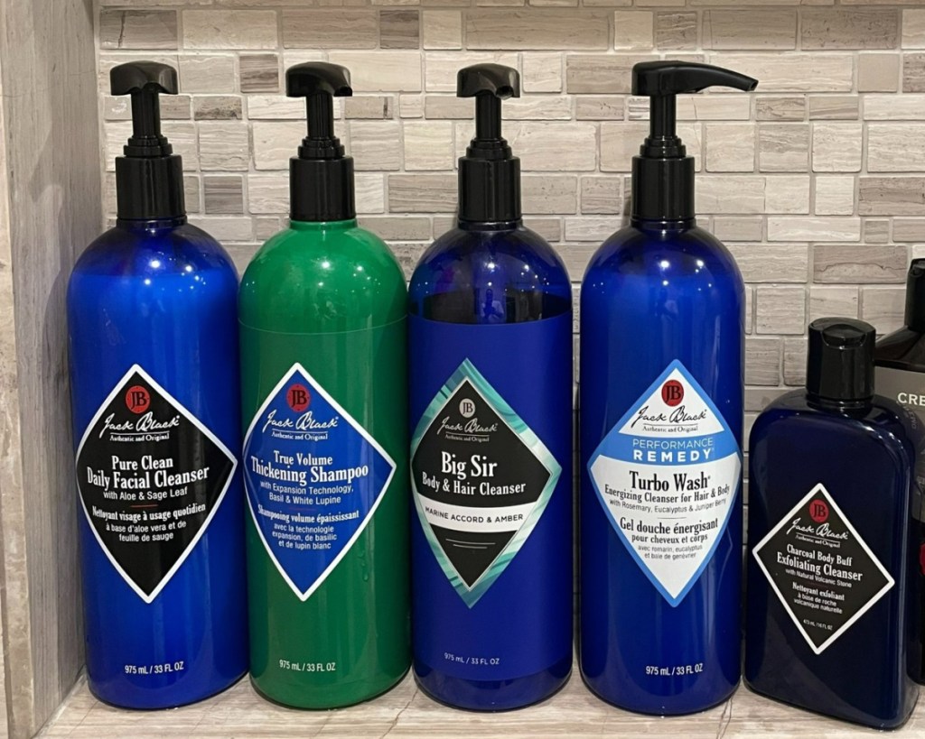 several large shampoo and face wash bottles in shower