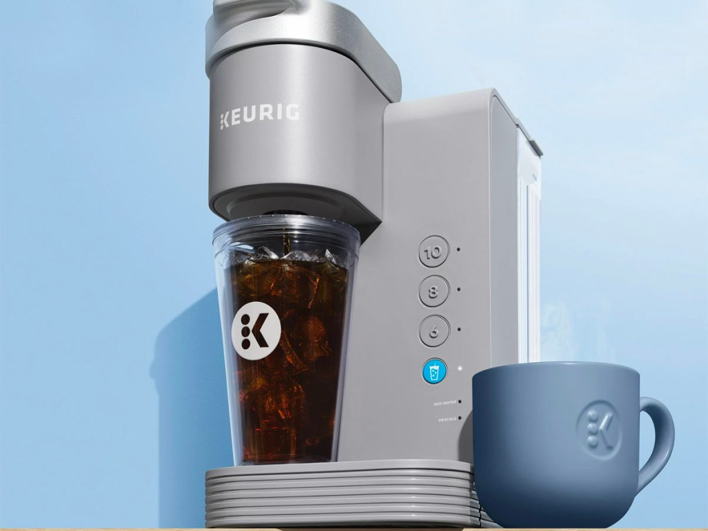 gray keurig iced coffee make brewing in tumbler with blue coffee mug next to it
