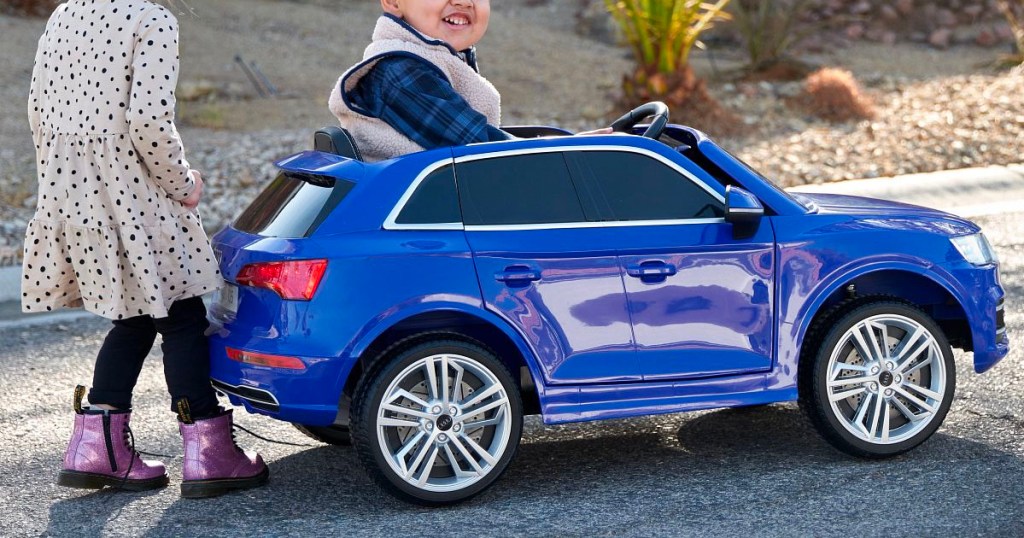 two children playing with kid trax blue audi car 