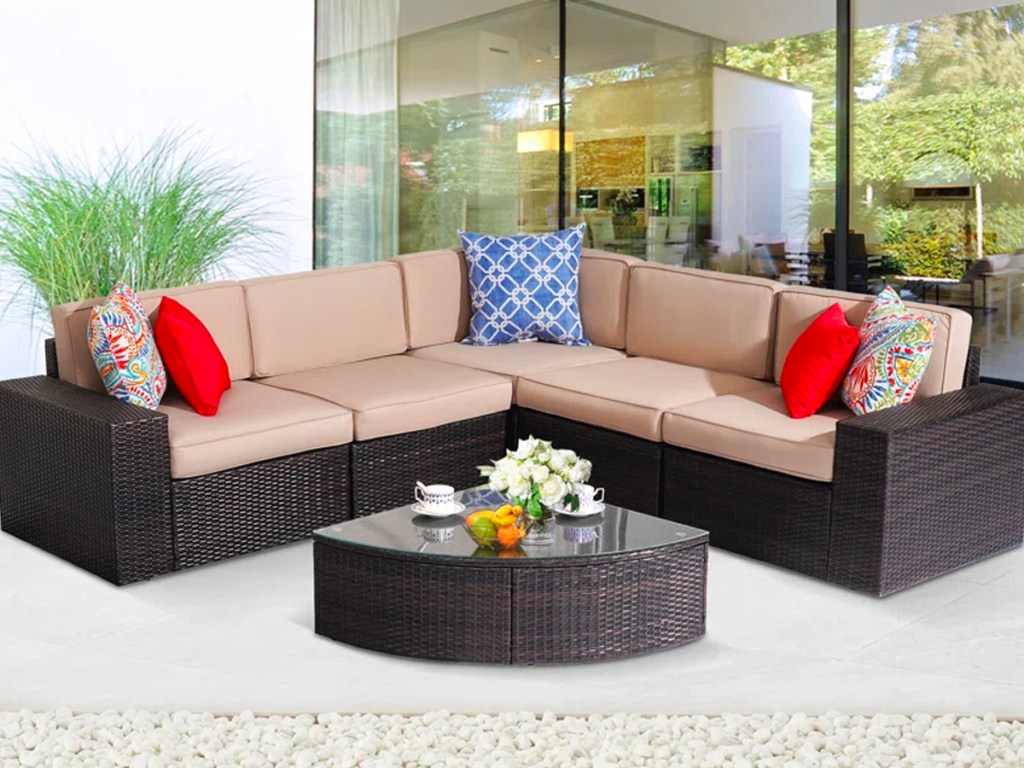 black sectional with tan cushions and red pillows on patio