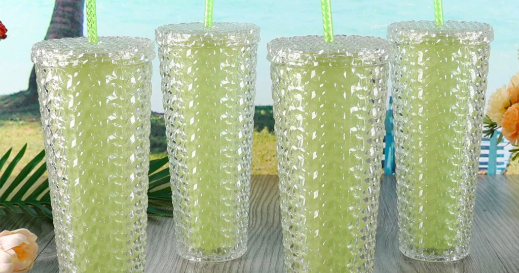 4 yellow studded tumblers on table with beach in background