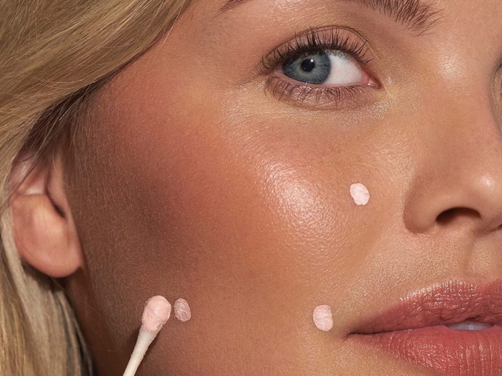 woman dotting mario badescu drying lotion on her face with a q-tip