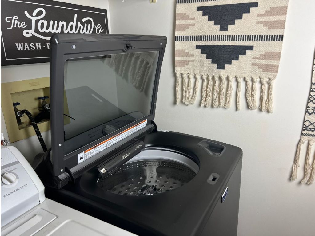black top load washer with lid up in laundry room