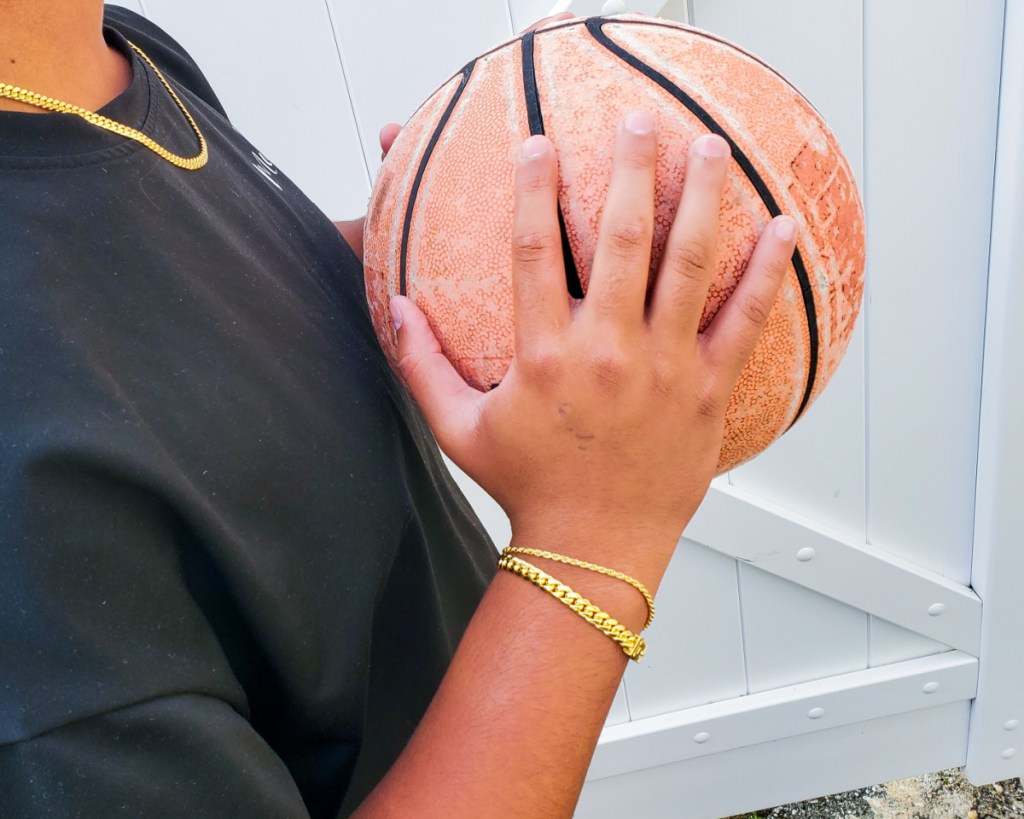 hand holding basketball wearing two cuban link bracelets
