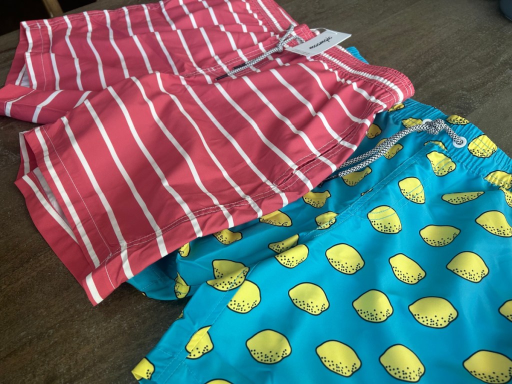 two pairs of mens swim trunks in fun prints laying on a flat surface