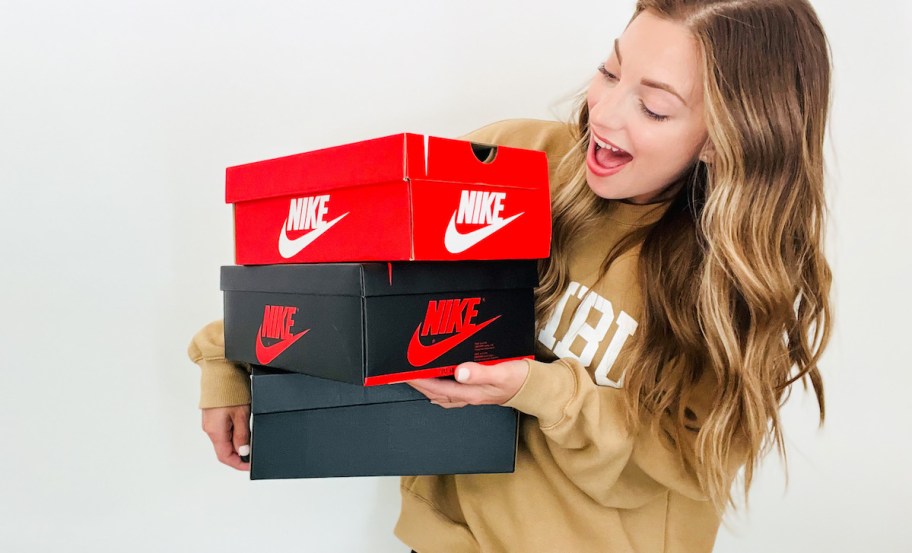 woman holding a stack of black and red nike boxes