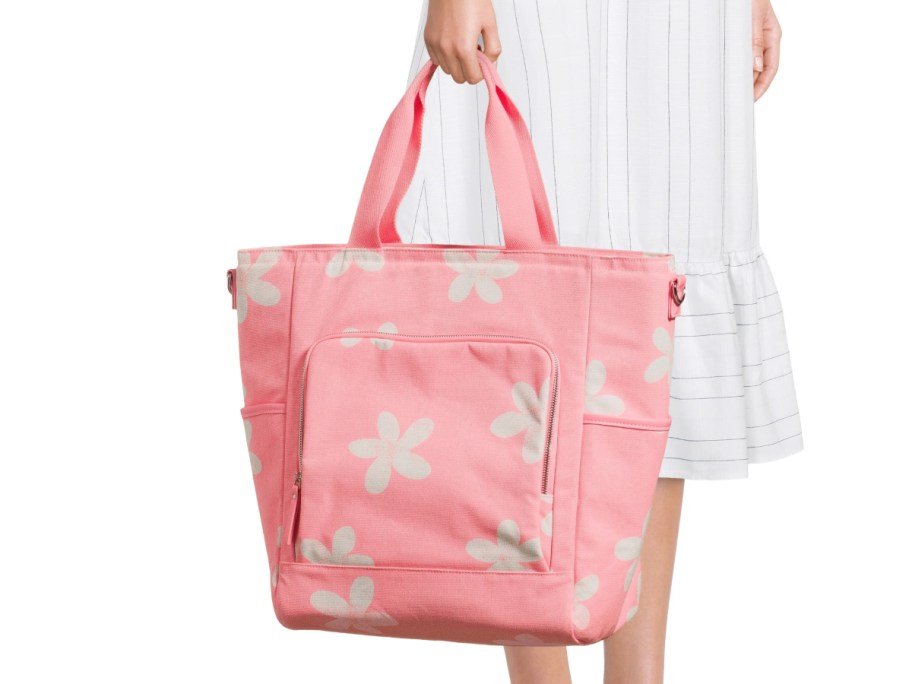 holding a pink floral tote bag 