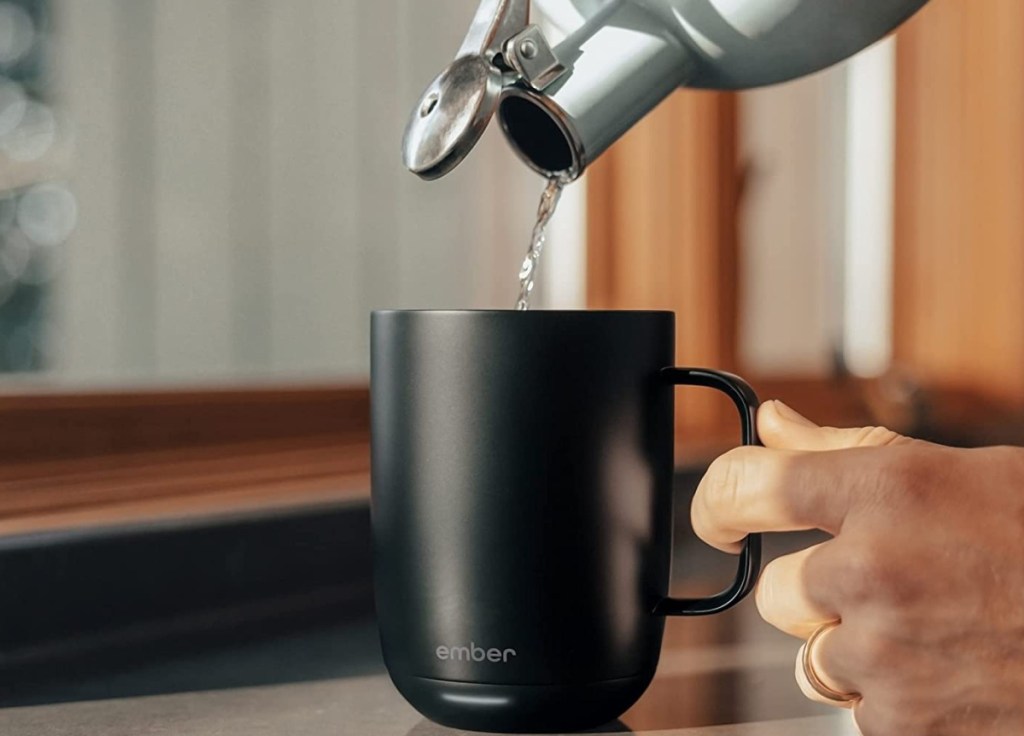person pouring hot water into ember coffee mug