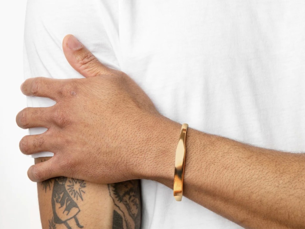 guy with white shirt crossing arms wearing gold bracelet