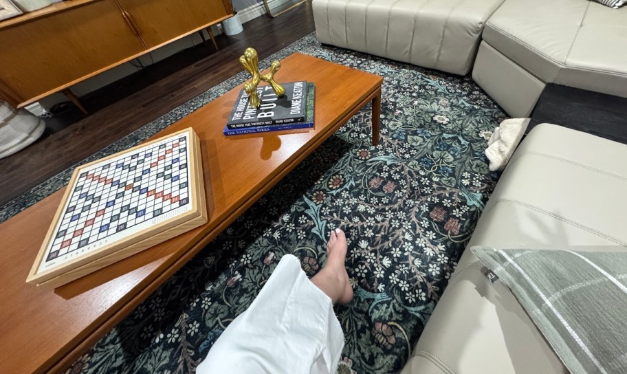 view of person sitting on couch with wood coffee table and floral rug