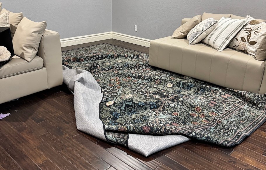 bunched up floral rug under beige sectional