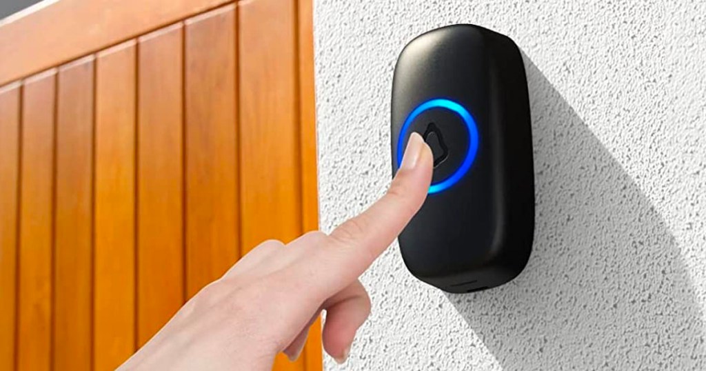finger pressing black doorbell on wall