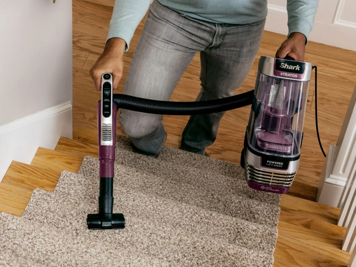 person using extender tool from shark vacuum on stairs