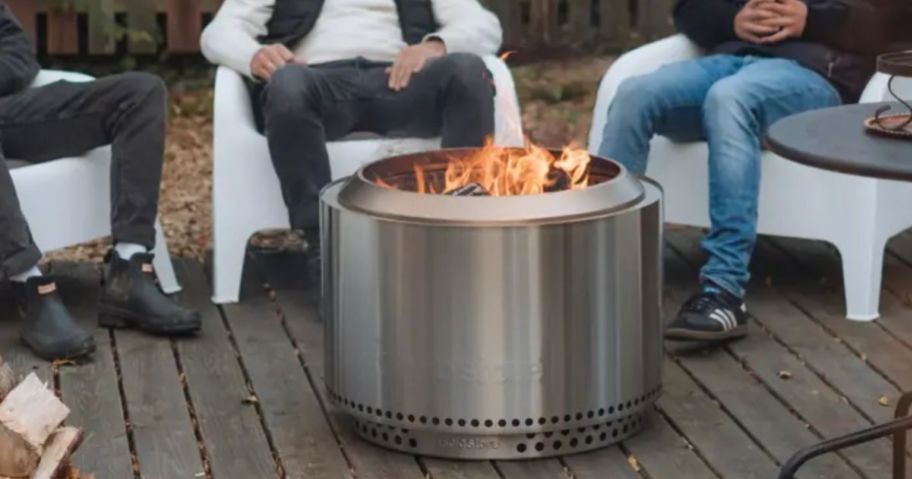3 people sitting around a large solo stove fire pit