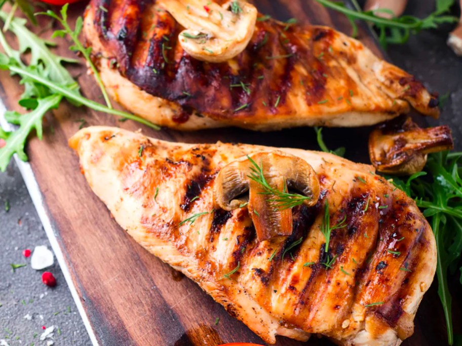chicken breast on cutting board with herbs