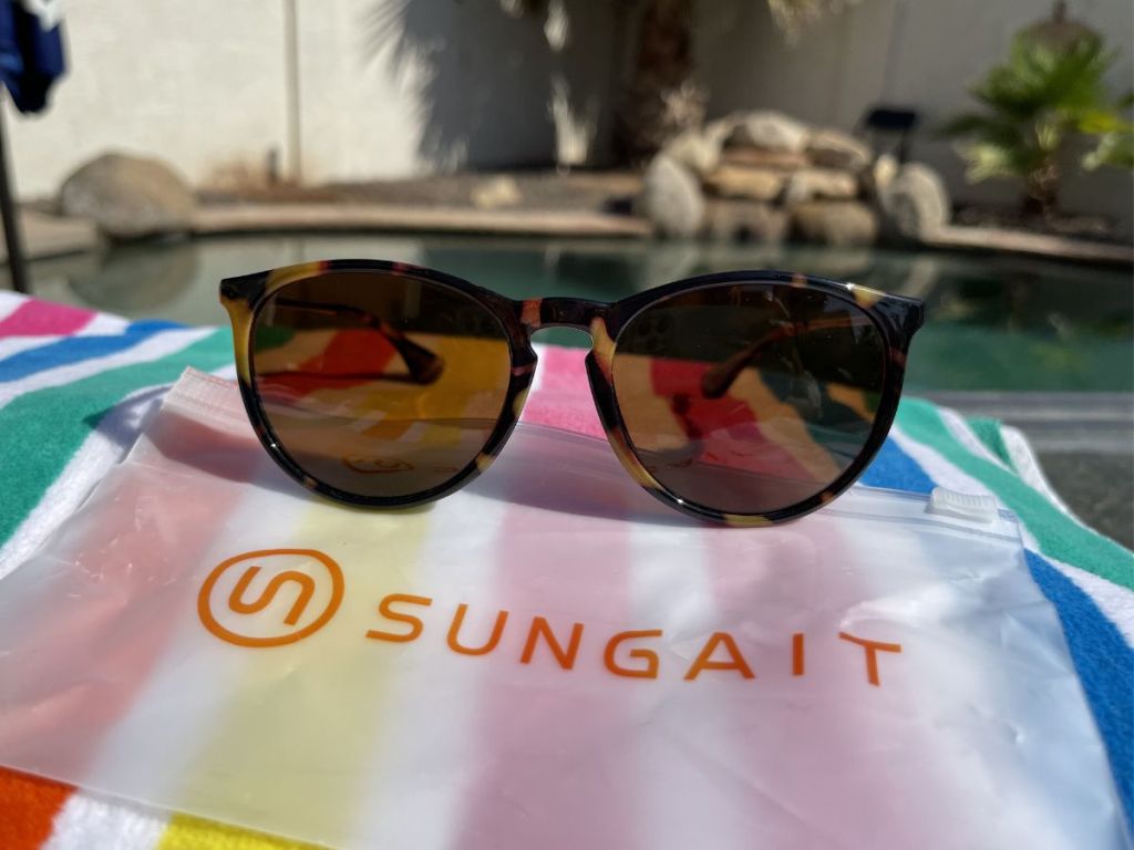 sunglasses sitting on Sungait bag with beach towel under bag