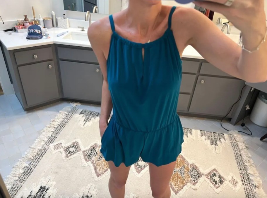 woman taking mirror selfie wearing blue swim romper with pockets