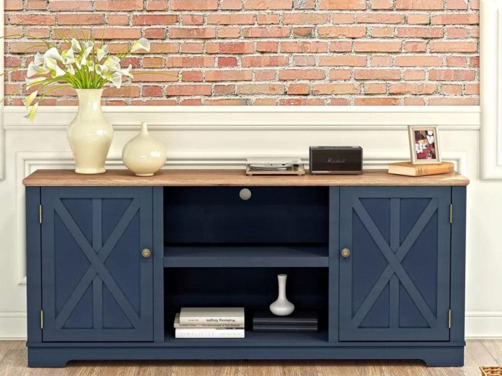 blue barn door TV stand with flowers and stature on it
