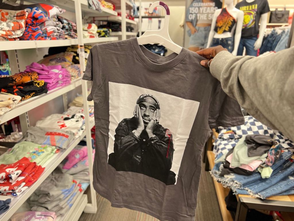 man holding Tupac graphic tee in store