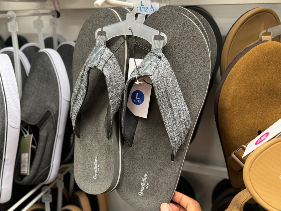 hand reaching for a grey pair of men's flip flop sandals on a display