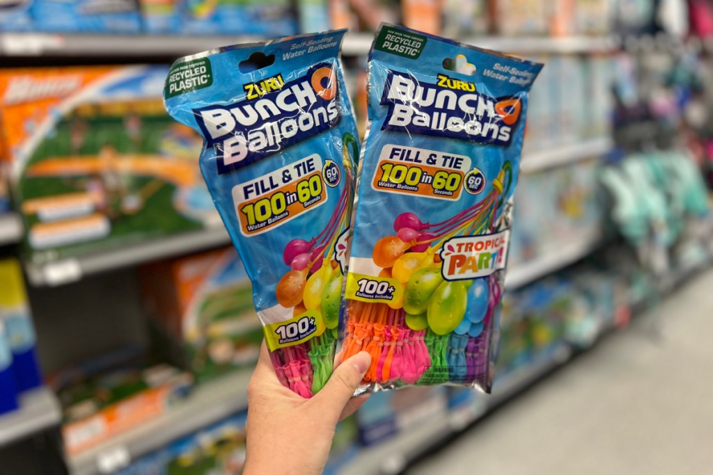 hand holding two packs of tropical colors zuru bunch o balloons in front of a store shelf