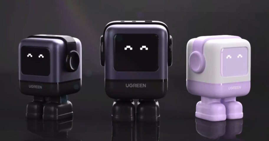 3 device chargers that look like little robots, 2 in black and one in purple and white, they have light up screens showing charging status