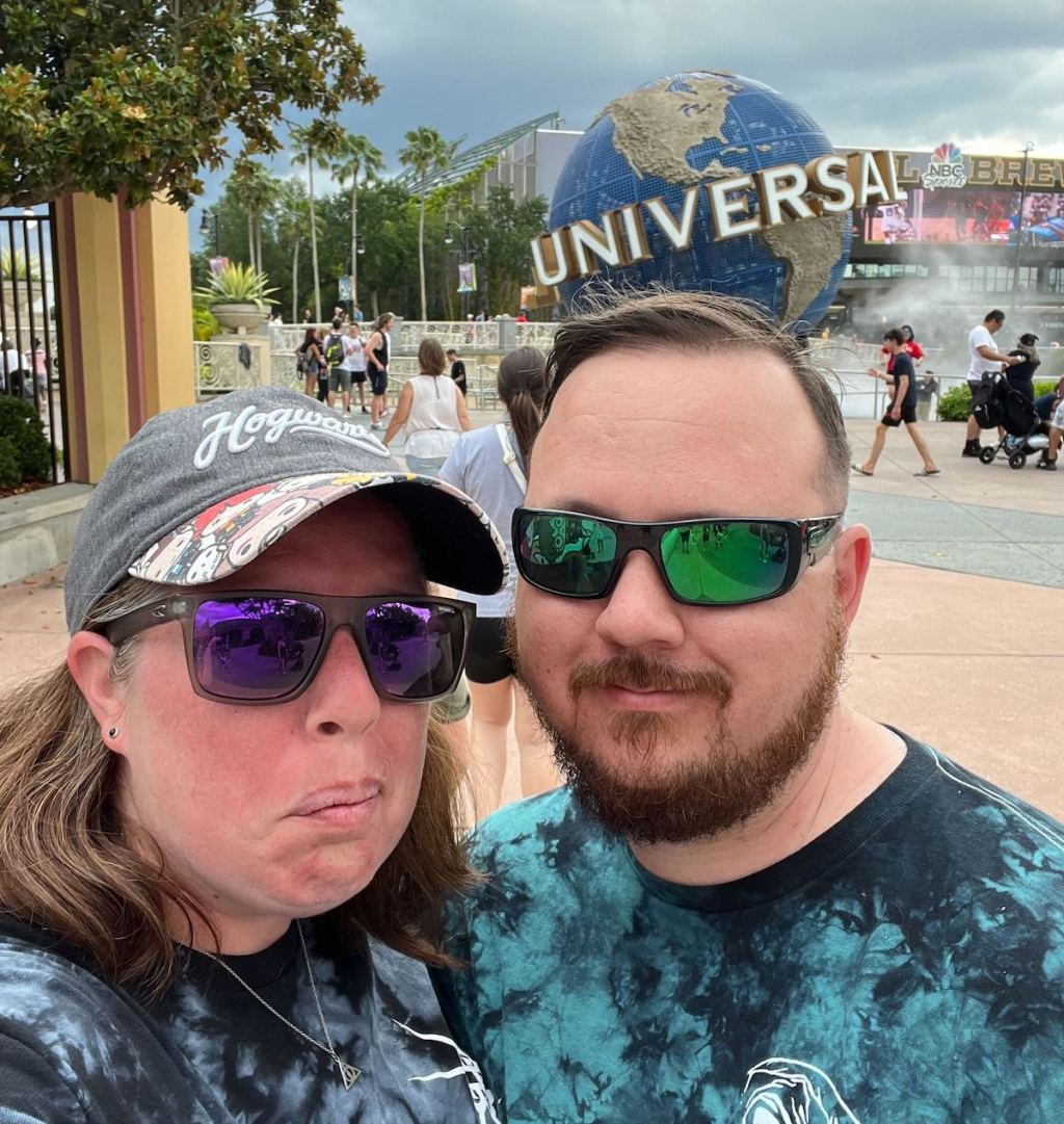 couple standing in front of universal studios globe at park