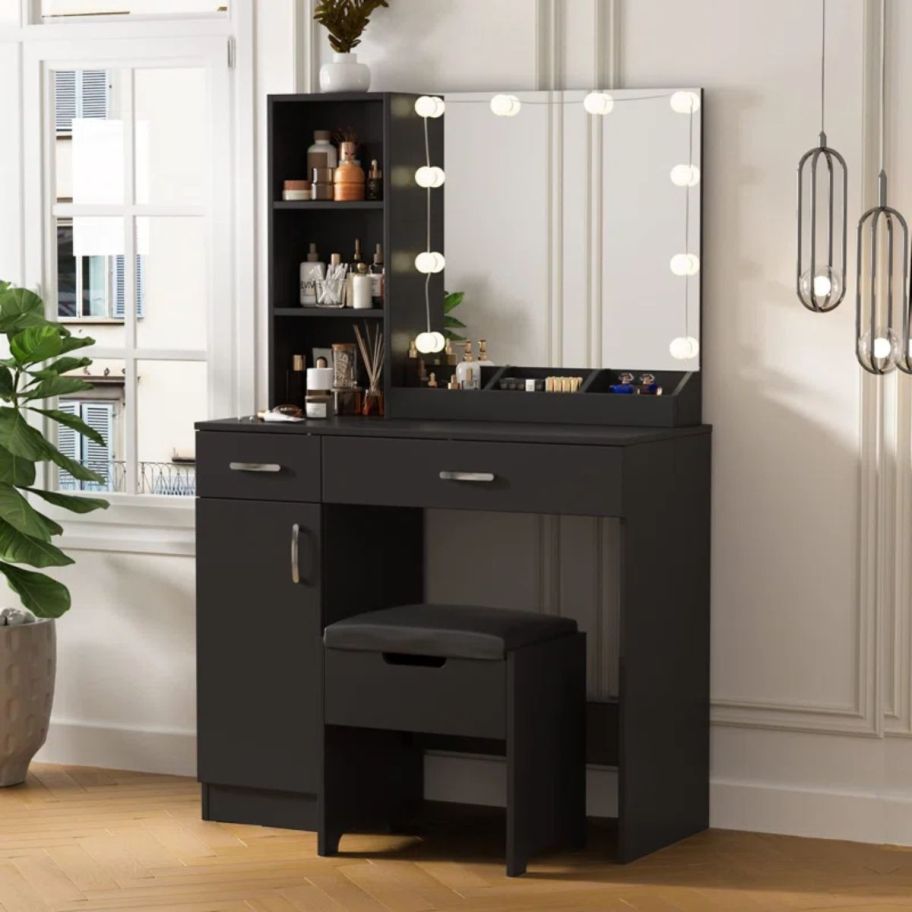 a black vanity desk with lighted mirror