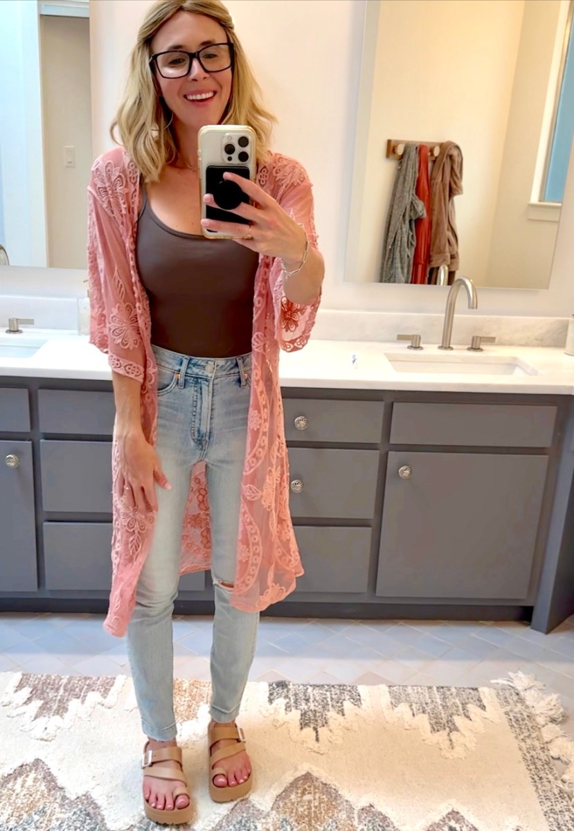 woman taking selfie in mirror wearing pink lace time and tru cover up with jeans