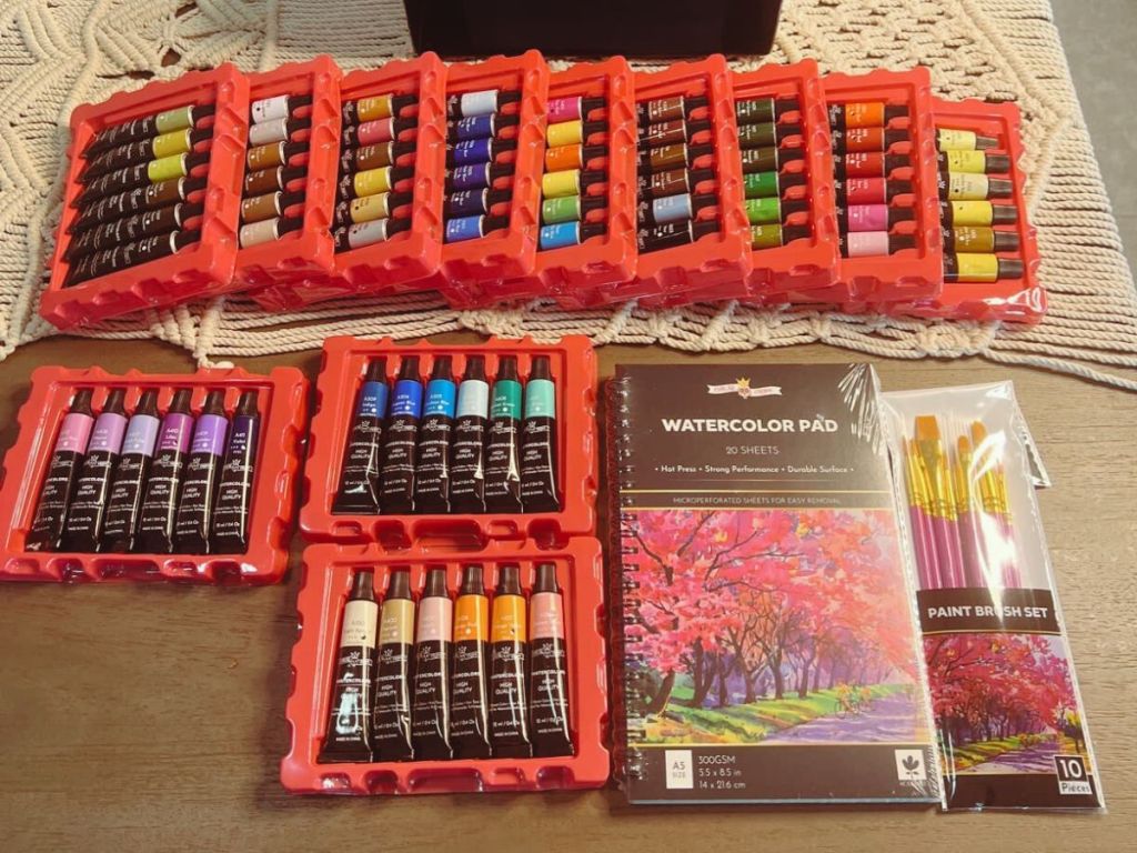 large watercolor paint set with watercolor pad and brushes laid out on table