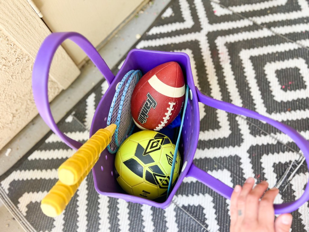 football soccer ball and more sports equipment in purple beach bag