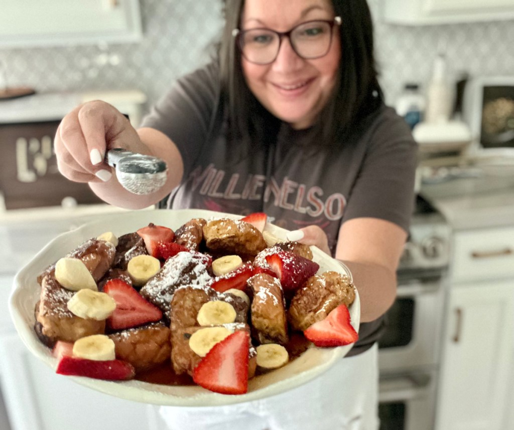 woman holding plate of french toast with powdered sugar