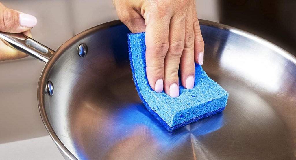woman using sponge on cooking pan