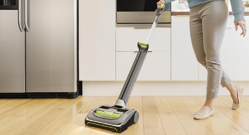 woman vacuuming her home with the BISSELL AirRam Cordless Vacuum in green