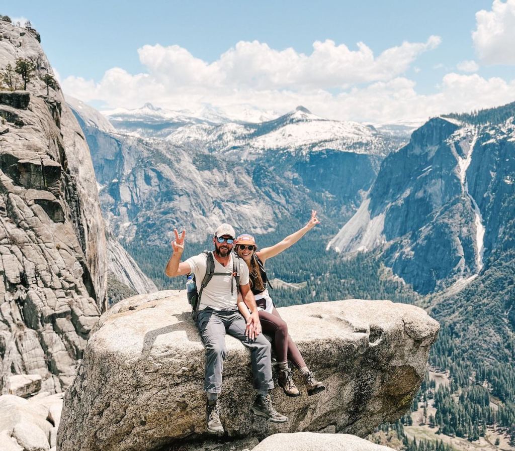 man and woman sitting on boulder in yosemite national park