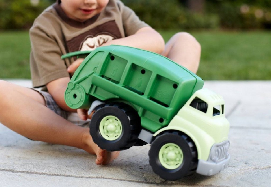 young child playing with Green Toys Recycling Truck outdoors