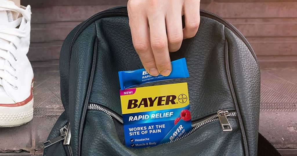hand putting Bayer Rapid Relief packs in purse