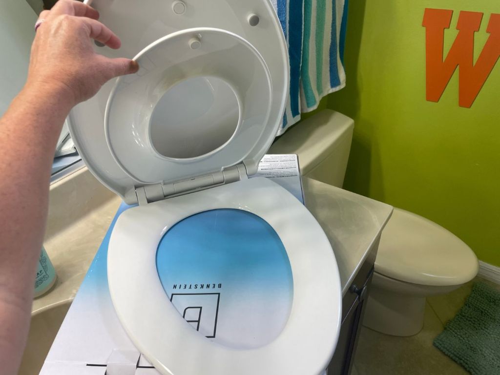 person taking toilet seat with toddler seat attached out of package