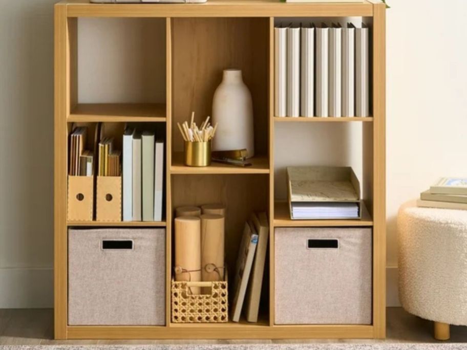 A brown cube organizer with books and boxes in it