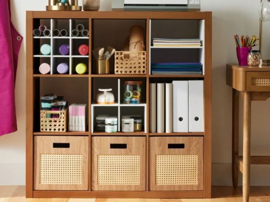 A brown cube organizer with books and boxes in it